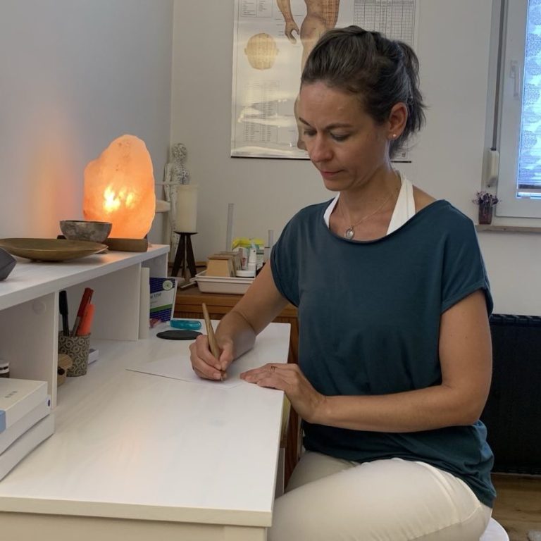 Heilpraktikerin Stephanie Bönisch am Schreibtisch Heilpraktikerin Stephanie Bönisch schreibt an ihrem Schreibtisch in der Praxis